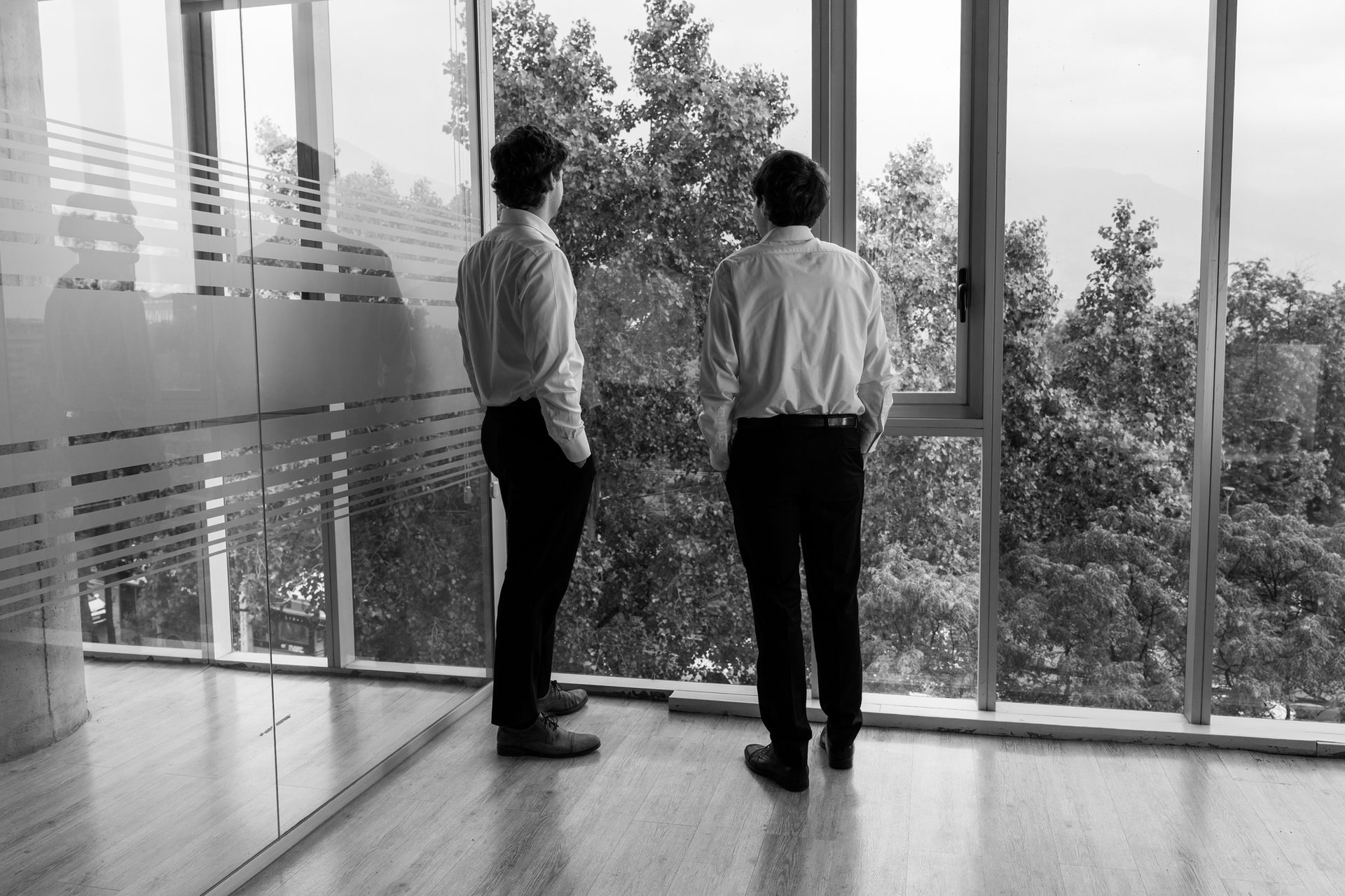 Dos profesionales de espaldas observando Santiago desde el ventanal de la oficina
